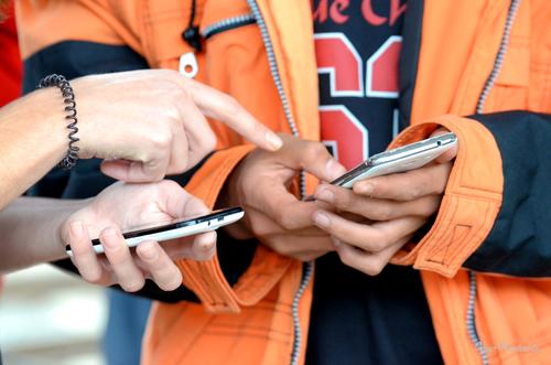 Ein Flüchtlingshelfer und ein Flüchtling am Bahnhof in Linz überwinden Sprachbarrieren mithilfe ihrer Smartphones (https://www.flickr.com/photos/79807353@N07/20981531288/). 